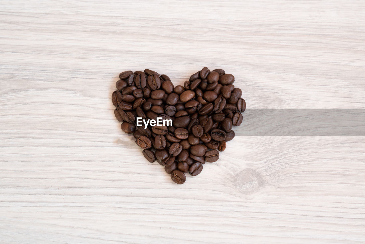 High angle view of heart shape made of roasted coffee beans on table