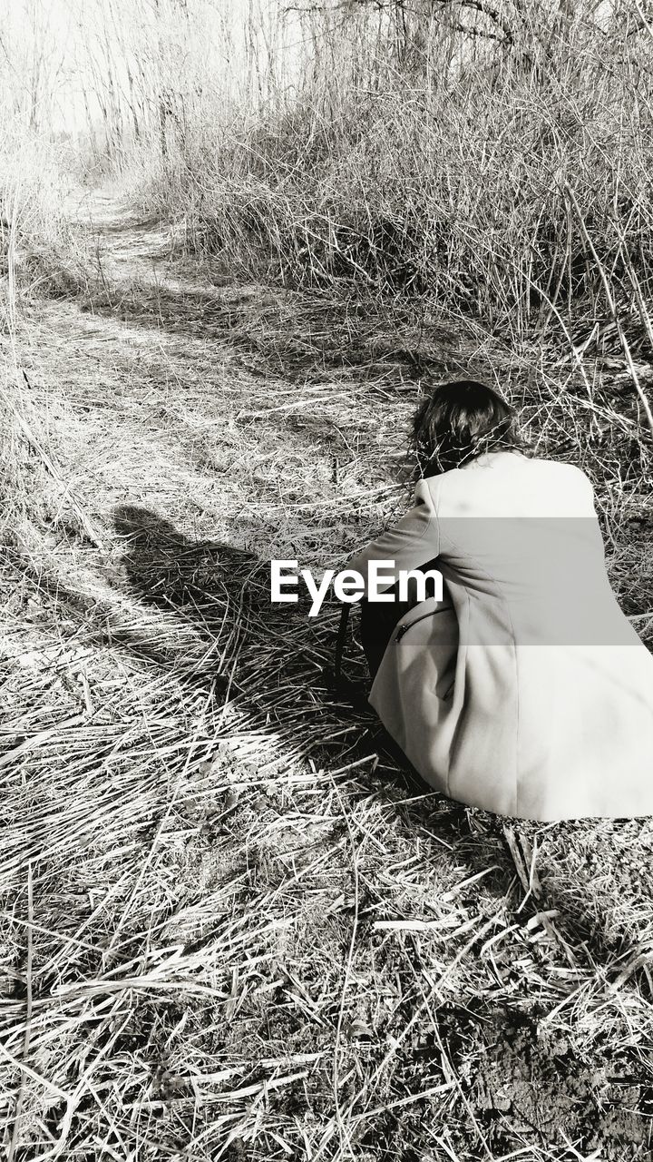 Woman crouching in dry grass