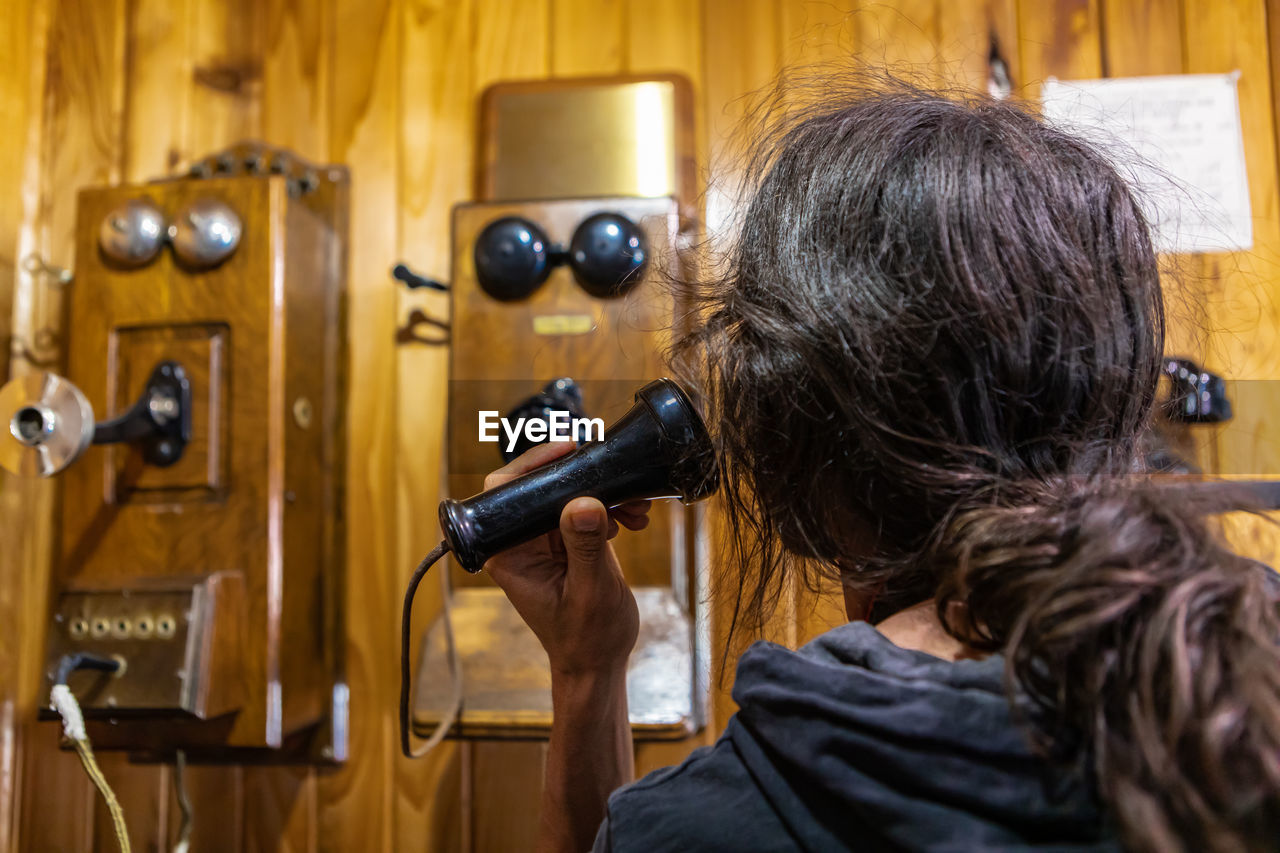 Rear view of woman holding vintage phone