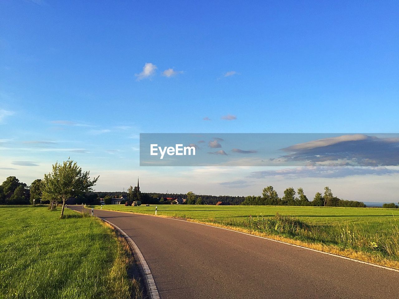 Road amidst field against sky