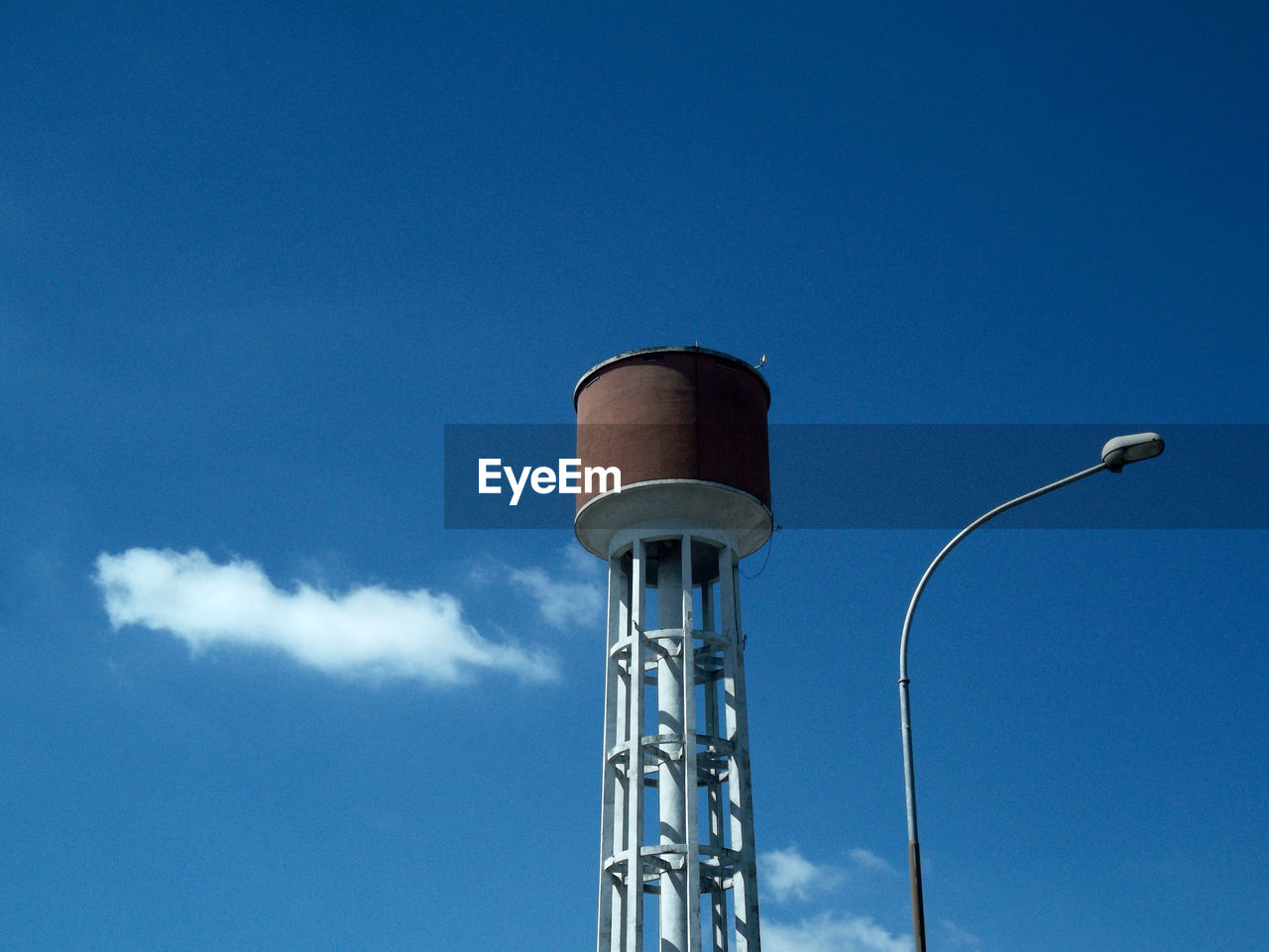 Piezometric tower with lamppost and clouds in a blue sky