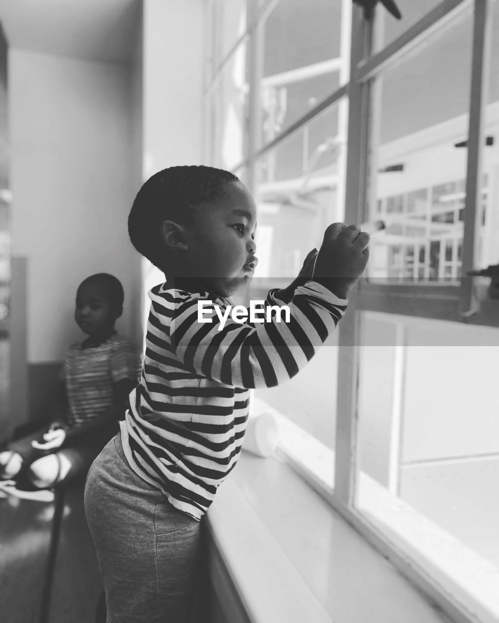 Side view of boy looking through window at home