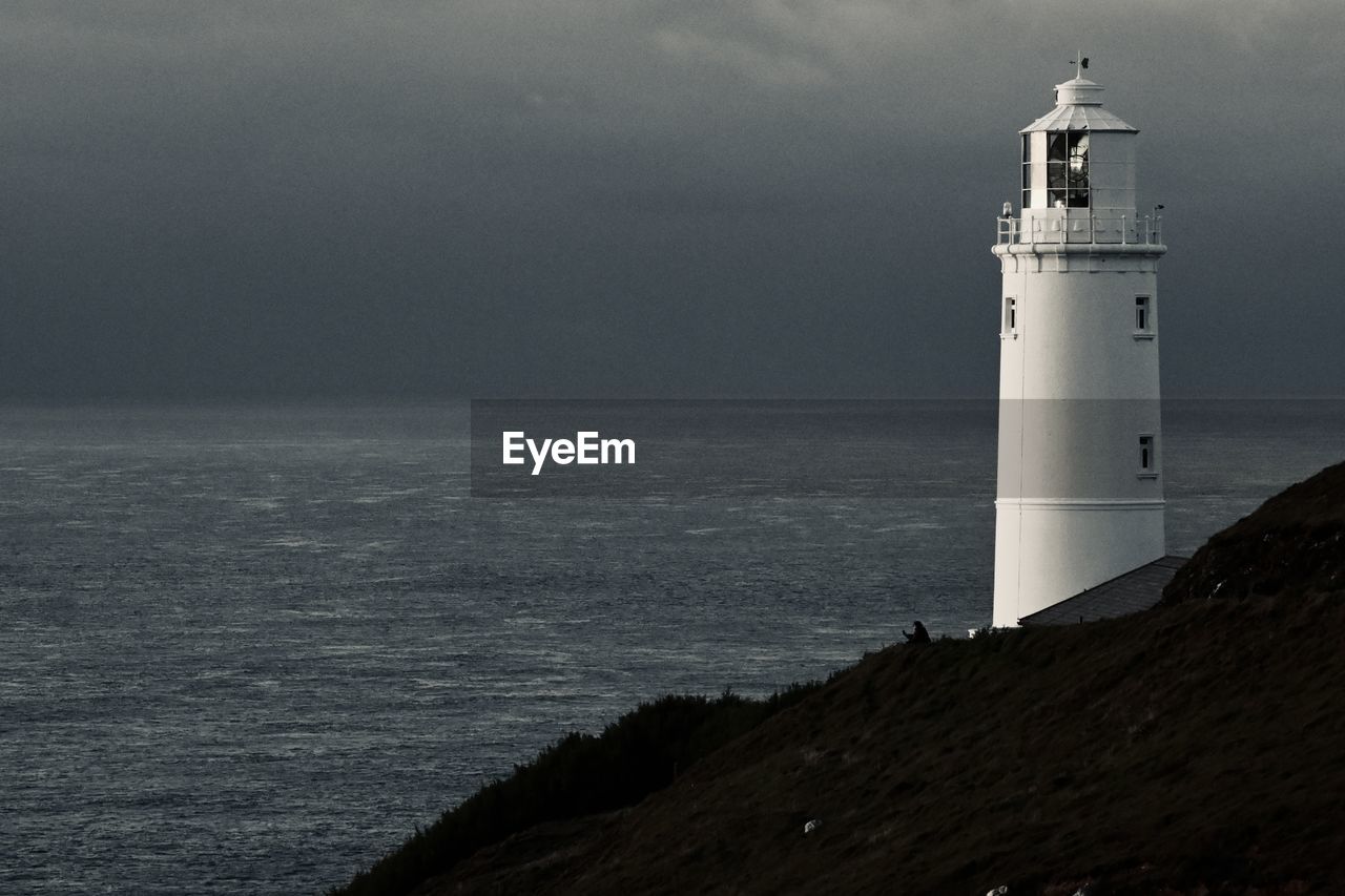 Lighthouse by sea against sky