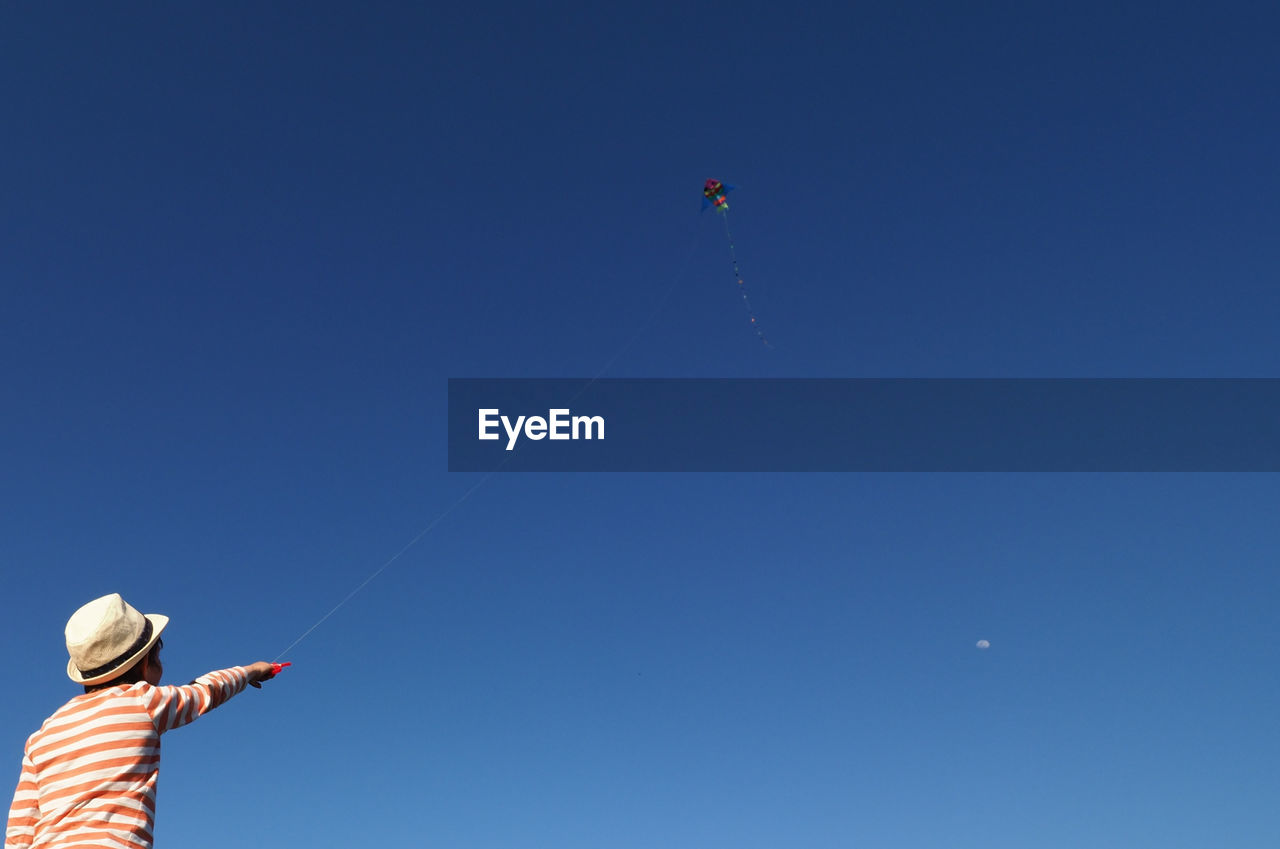 Low angle view of man flying kite against sky