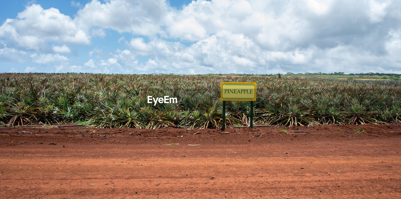 Information sign on field against sky