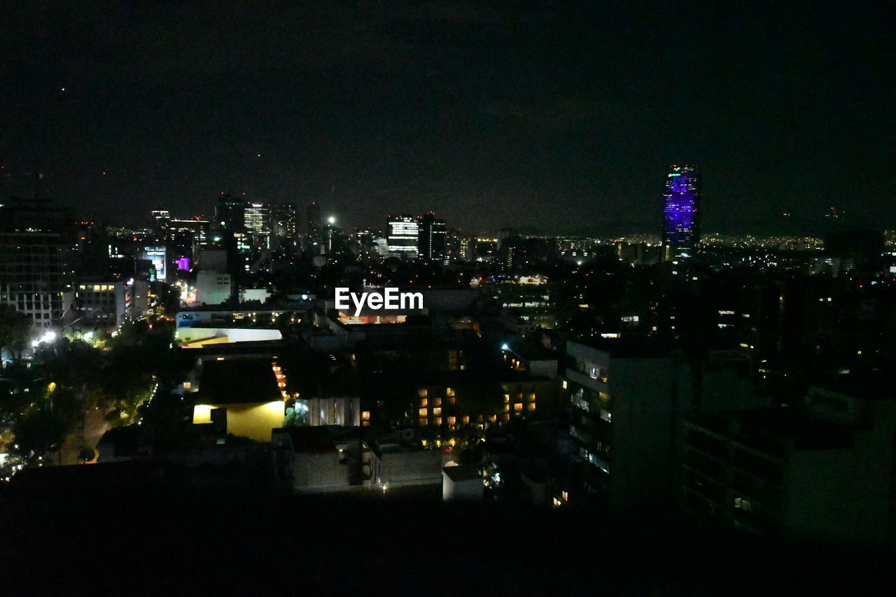 HIGH ANGLE VIEW OF ILLUMINATED CITY BUILDINGS AT NIGHT