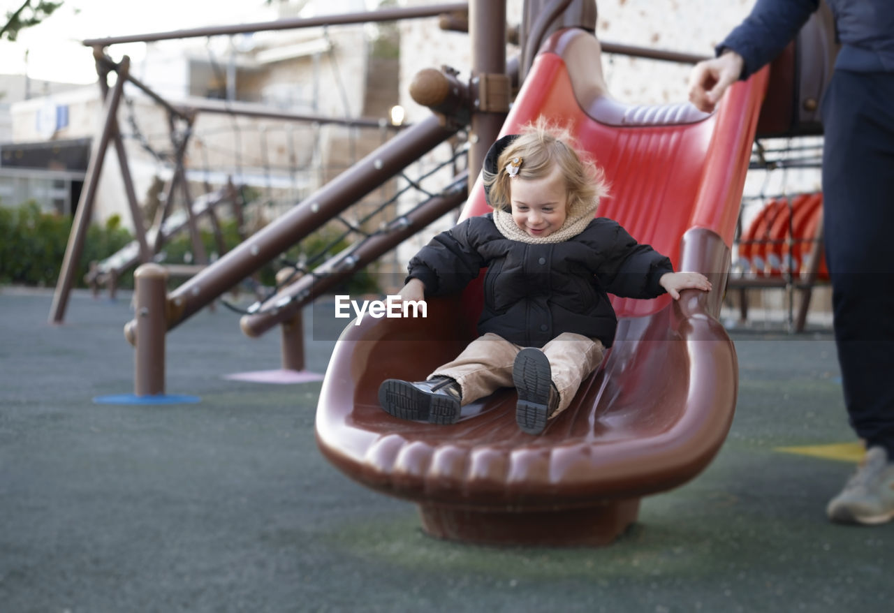 Happy baby girl sliding,warm clothing child,kid,toddler, infant of 1-2 year having fun in playground