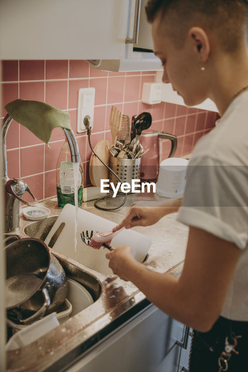 Woman in kitchen washing dishes