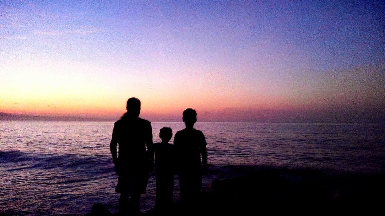 SILHOUETTE OF COUPLE STANDING ON SEA