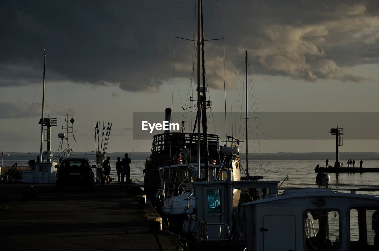 SAILBOATS MOORED AT HARBOR AGAINST SKY