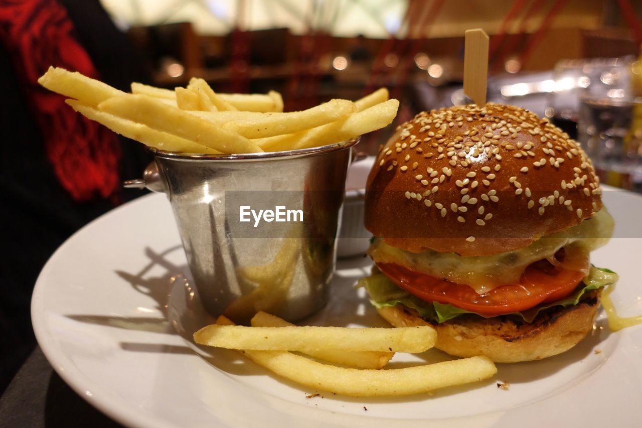 CLOSE-UP OF BURGER AND FRIES ON TABLE