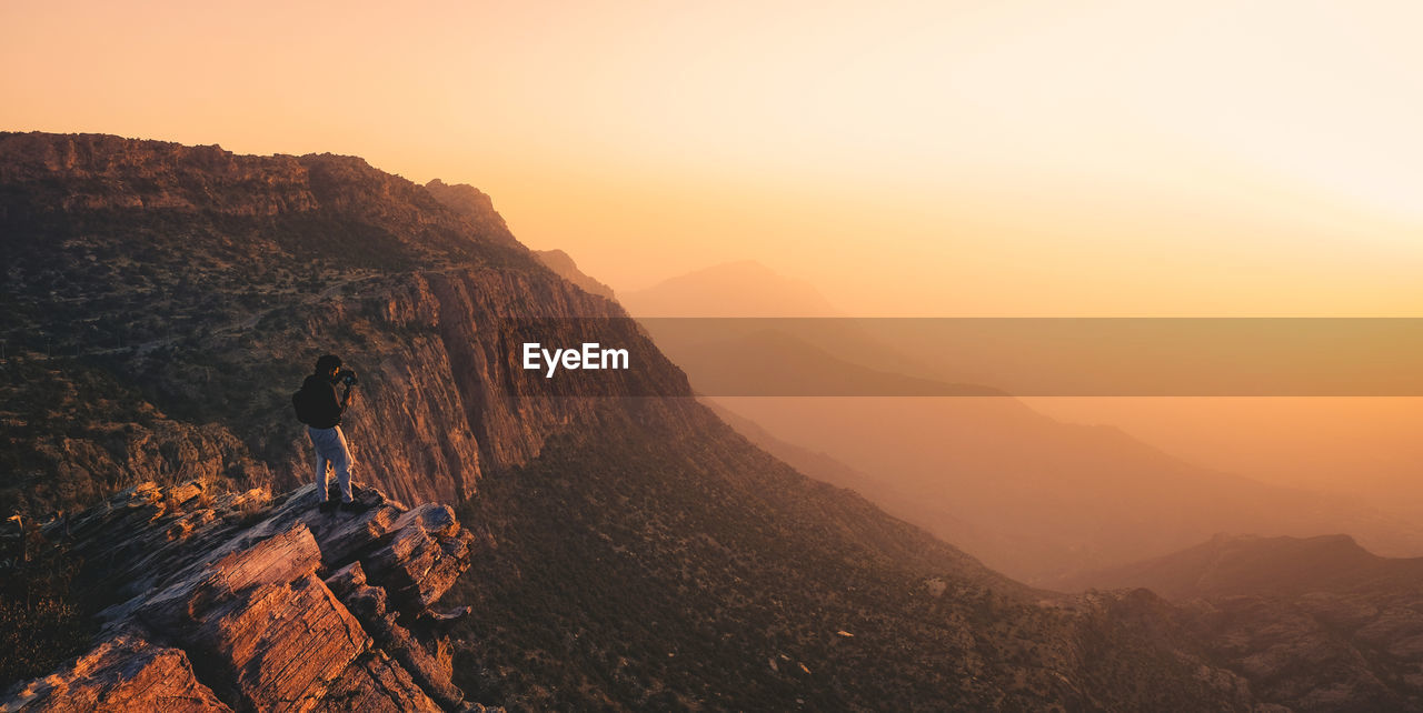 A man on the ledge of a cliff in tanomah, saudi arabia