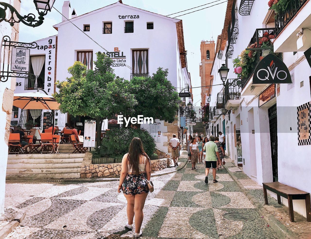 REAR VIEW OF PEOPLE WALKING ON STREET AGAINST BUILDINGS IN CITY