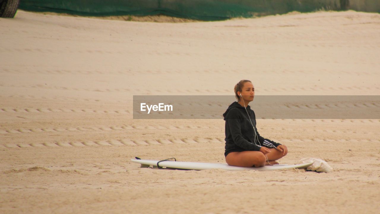 YOUNG MAN SITTING ON BEACH