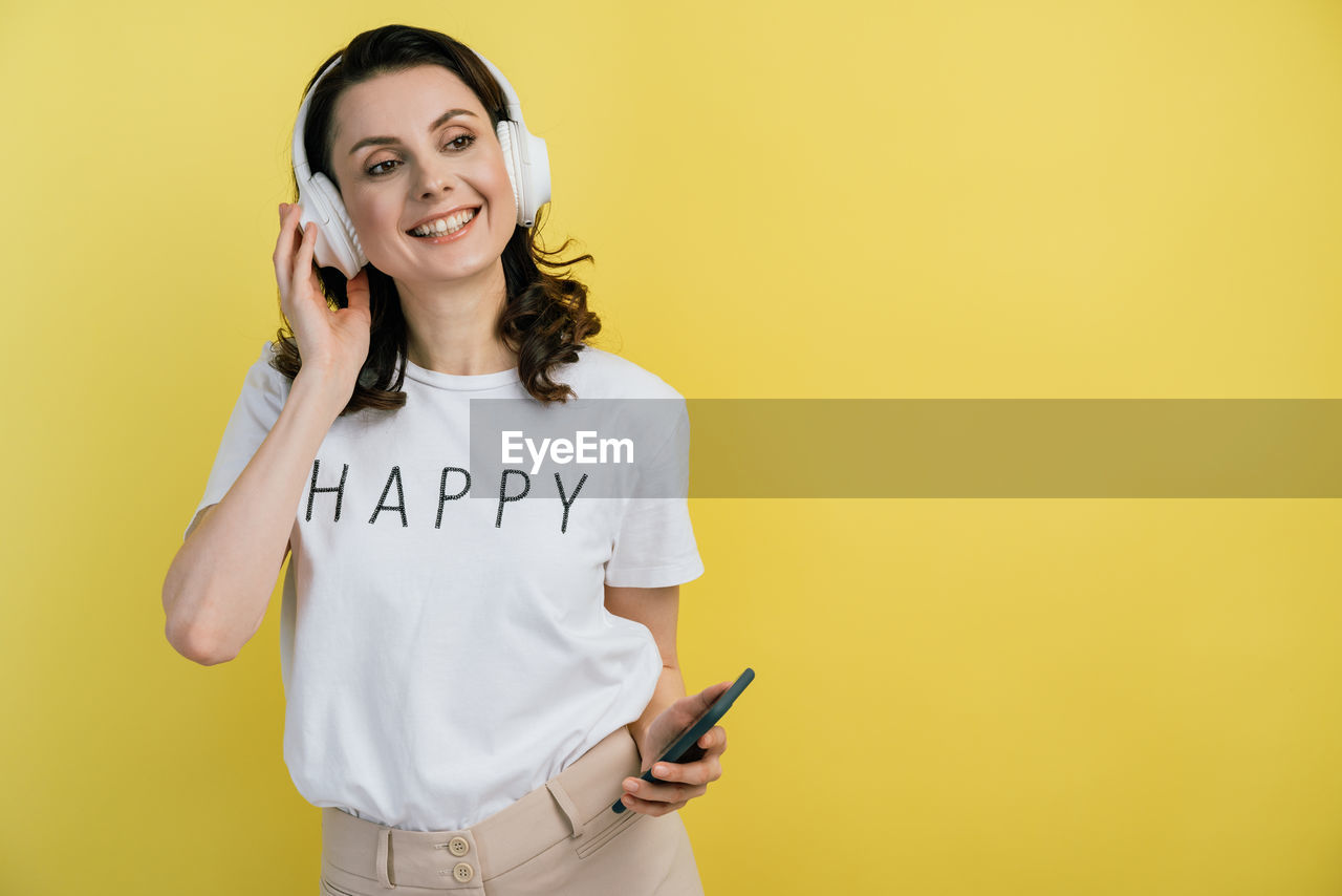 PORTRAIT OF SMILING WOMAN HOLDING SMART PHONE