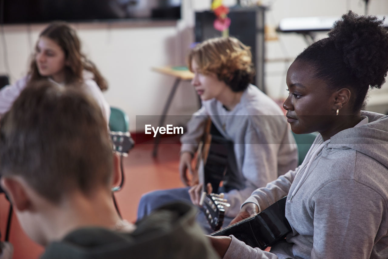 Teenagers attending guitar lesson