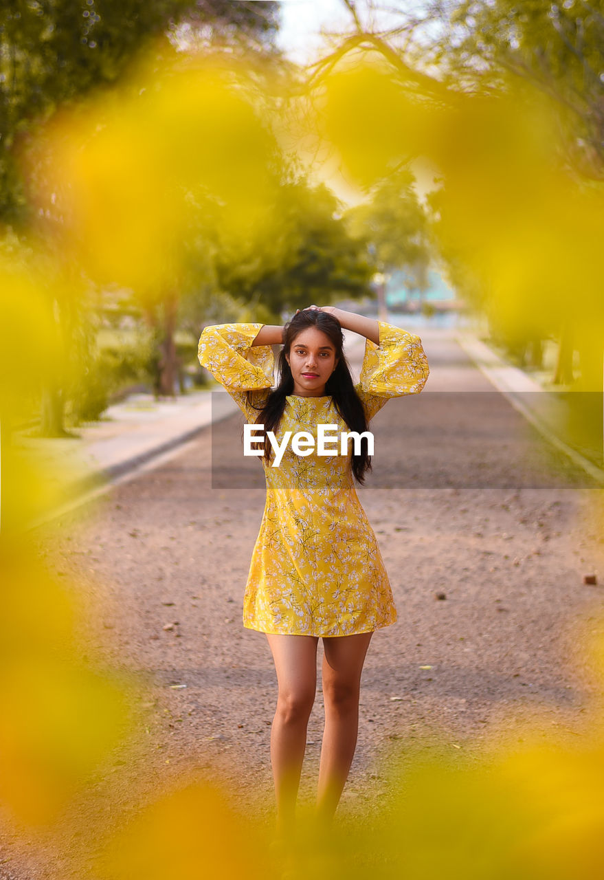 Portrait of woman standing on footpath