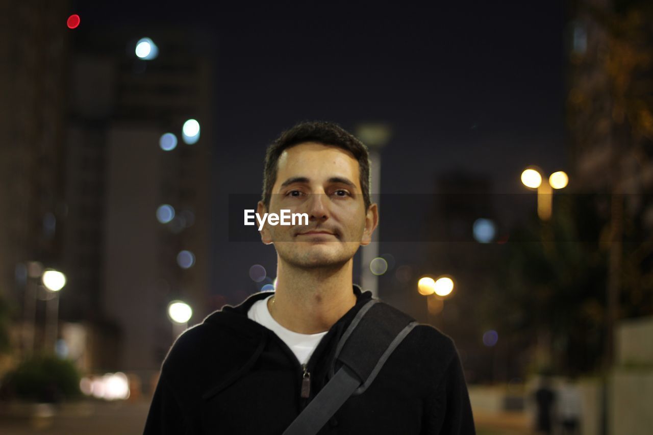 Portrait of smiling man in city at night