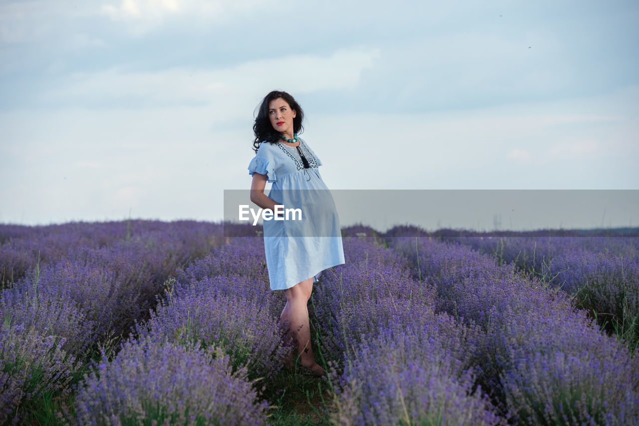 Woman with umbrella on field against sky