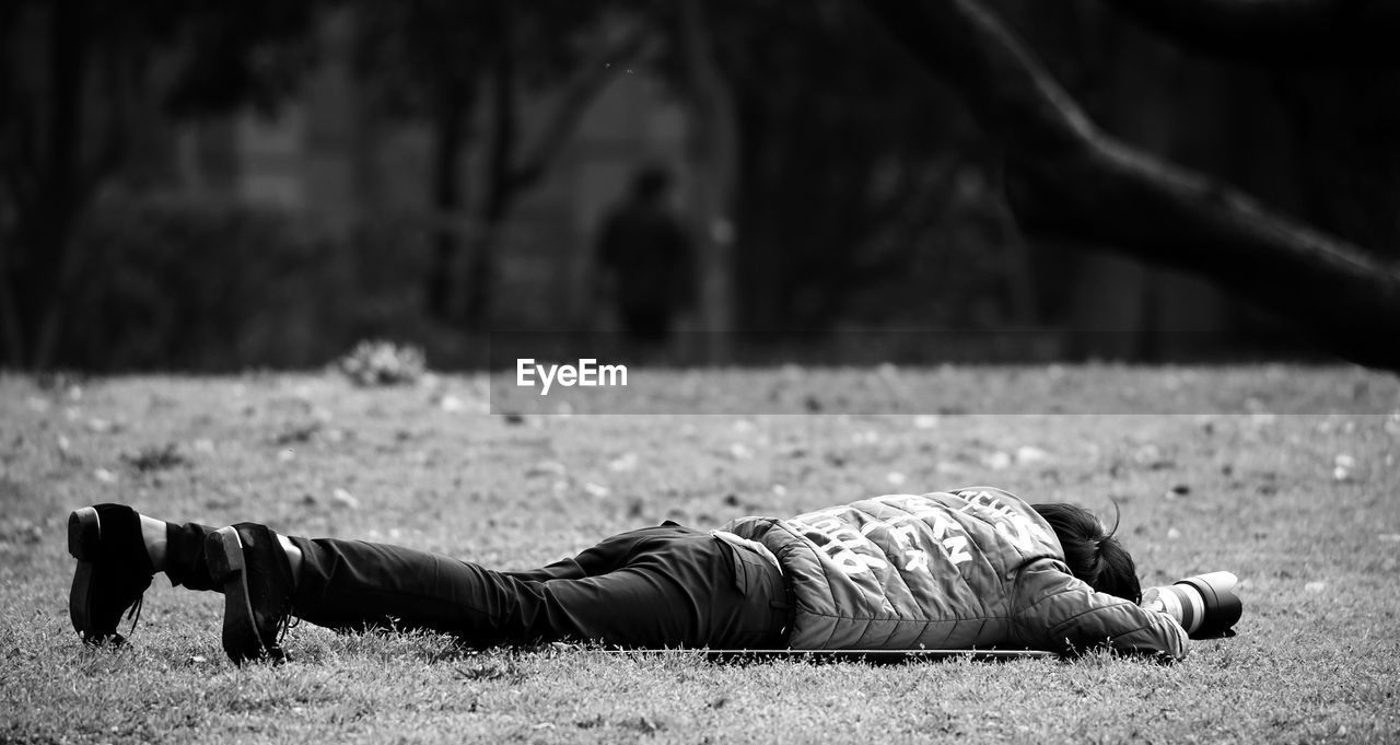 Close-up of man photographing while lying down outdoors
