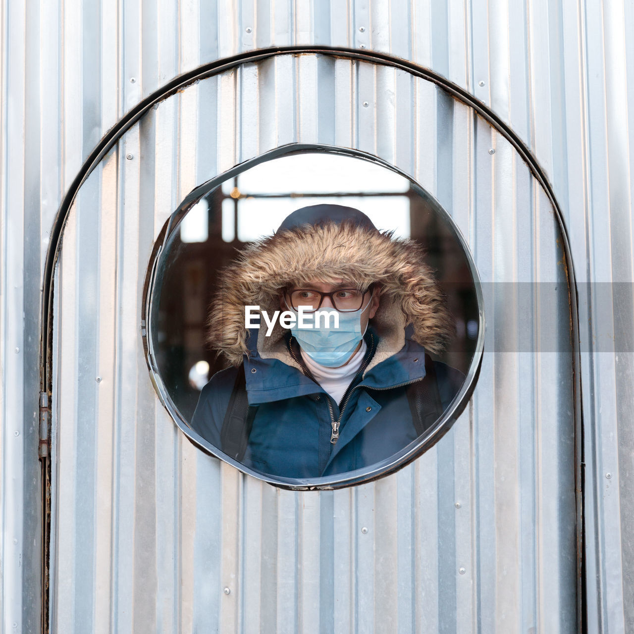 Man wearing mask looking through window