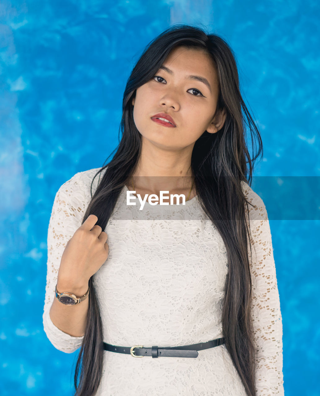 Portrait of beautiful young woman against blue wall