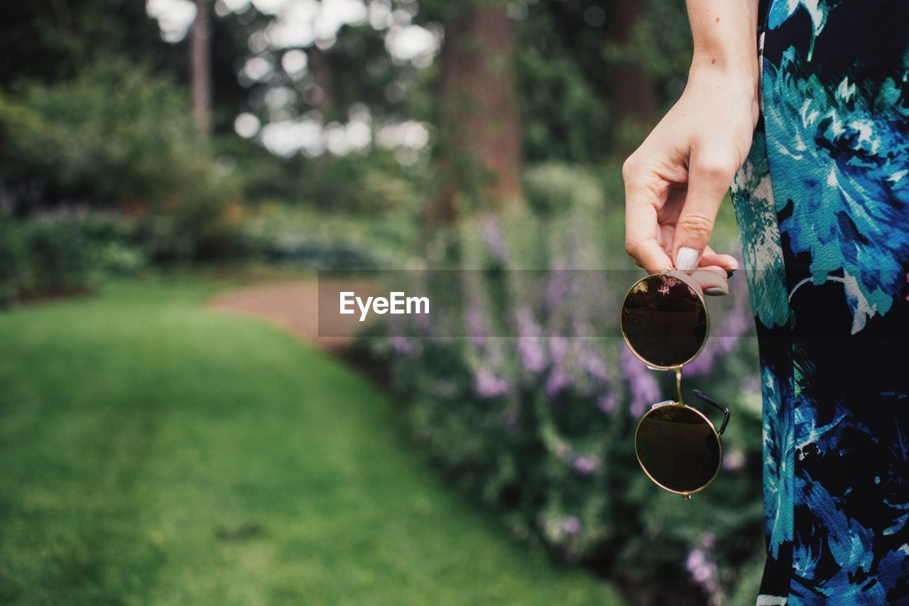 Cropped image of woman holding sunglasses at park