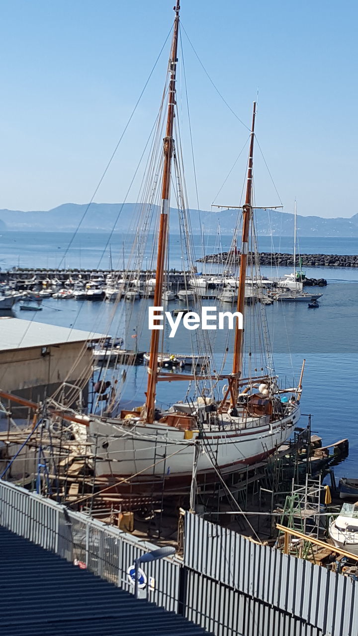 SAILBOATS MOORED AT HARBOR