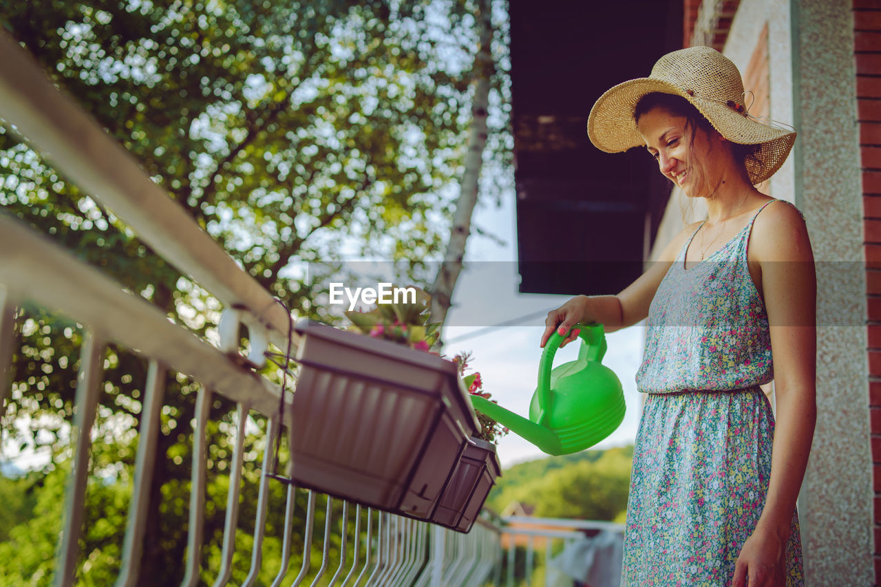 Young beautiful woman watering plants