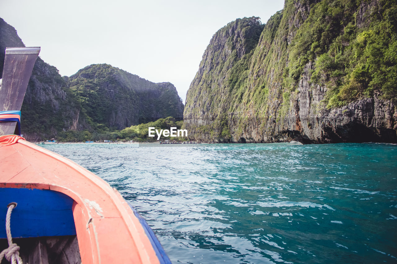 Boat sailing on sea by mountain against sky