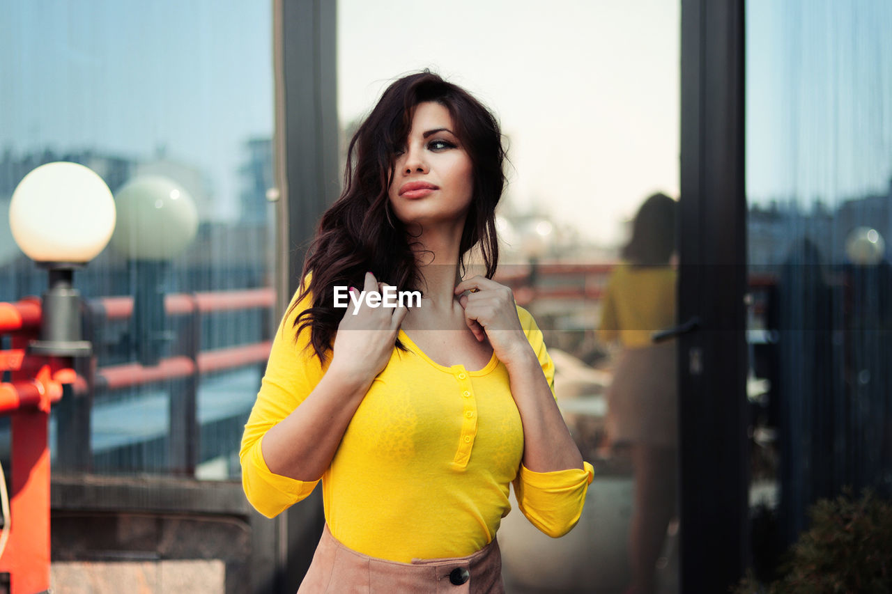 Young woman standing against glass wall