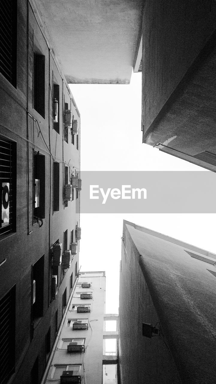 Directly below shot of modern buildings against clear sky