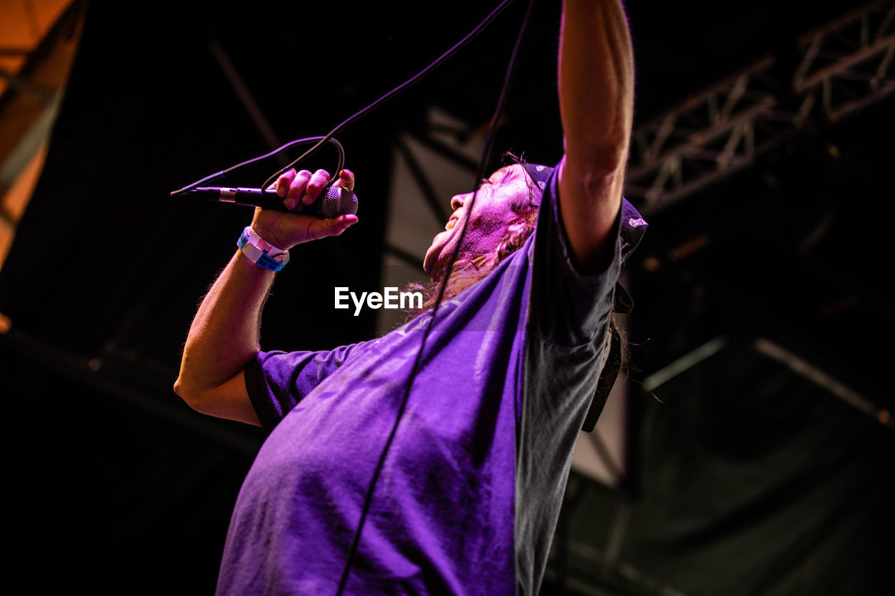 MIDSECTION OF MAN HOLDING UMBRELLA WHILE STANDING ON STAGE