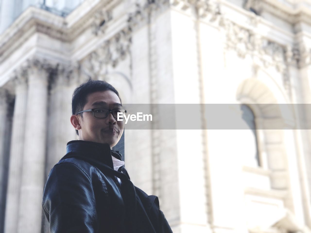 Low angle portrait of young man standing against st paul cathedral