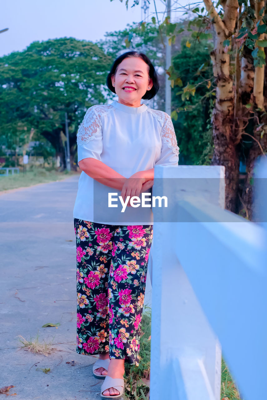 Portrait of smiling woman standing against plants