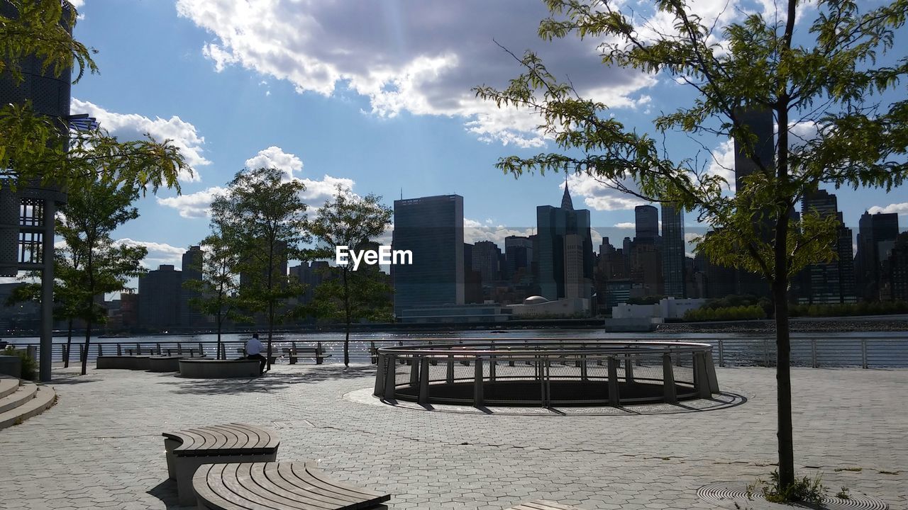 Park by lake against sky in city