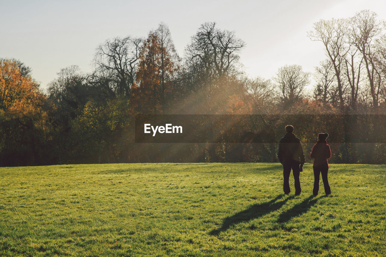 Rear view of couple standing on field at park