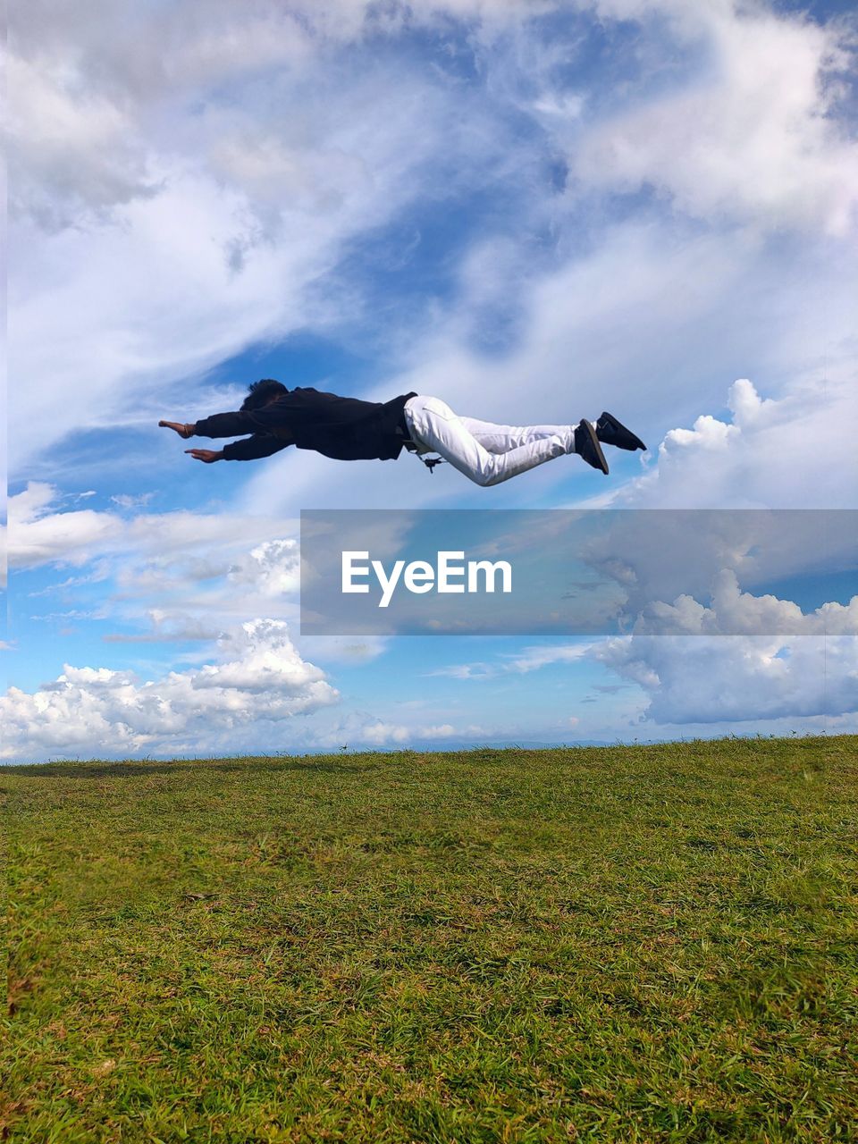 Young man levitating over land against sky