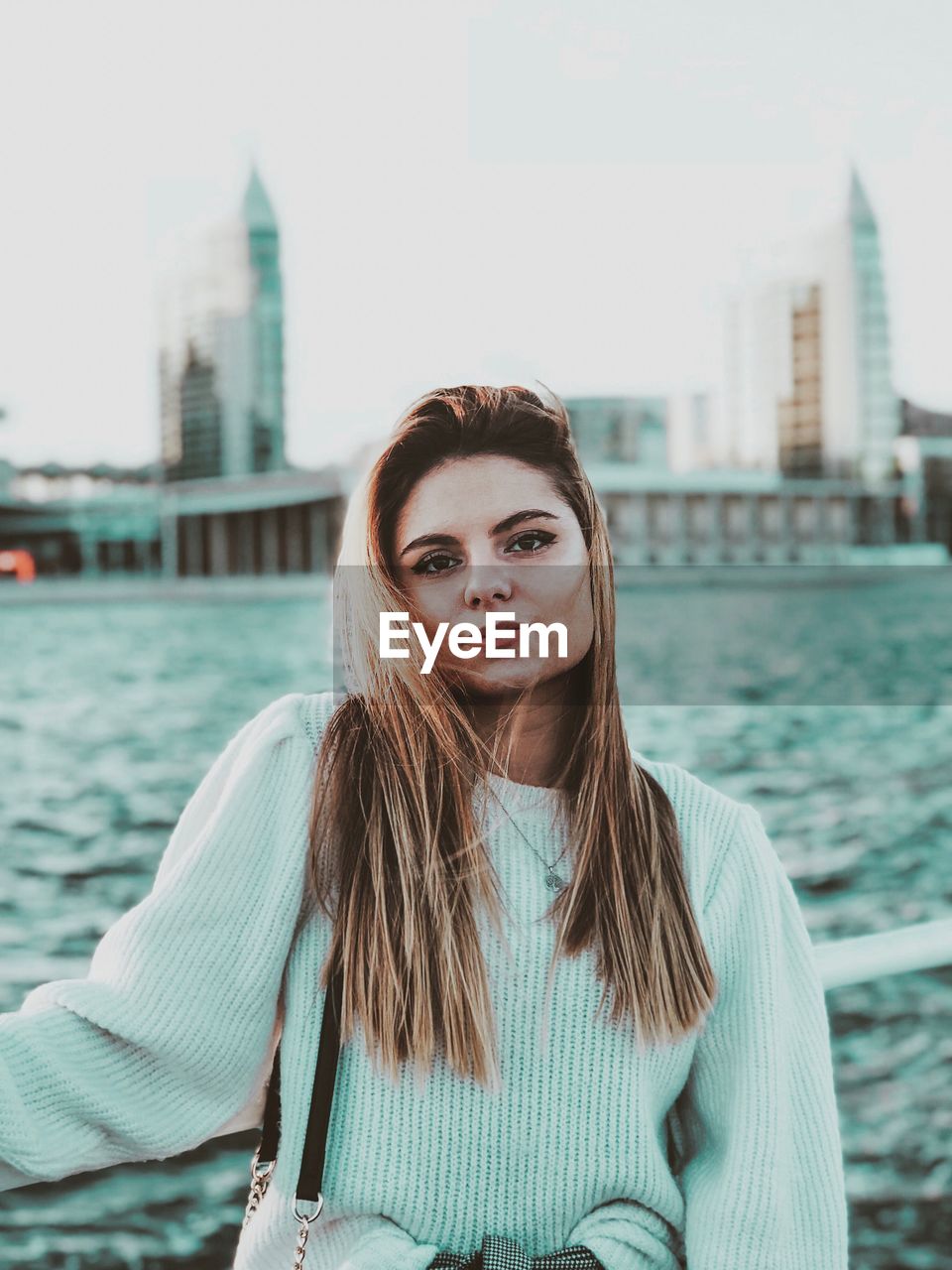 PORTRAIT OF BEAUTIFUL YOUNG WOMAN STANDING AT CITY
