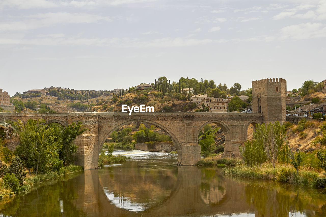 Arch bridge over river against sky
