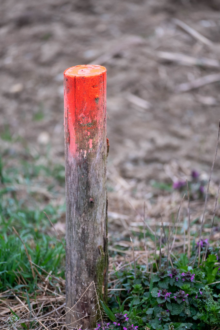 CLOSE-UP OF RUSTY METAL ON WOODEN POST AT FIELD