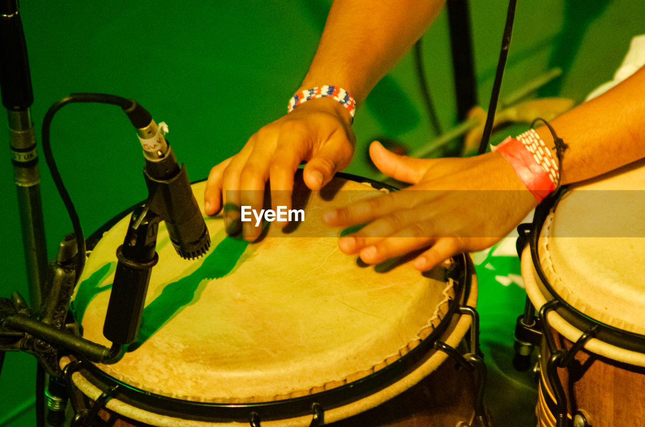 music, arts culture and entertainment, drum, hand, membranophone, percussion, musical instrument, drum - percussion instrument, musical equipment, performance, drums, musician, drummer, person, event, percussion instrument, yellow, adult, hand drum, green, one person, skill, close-up