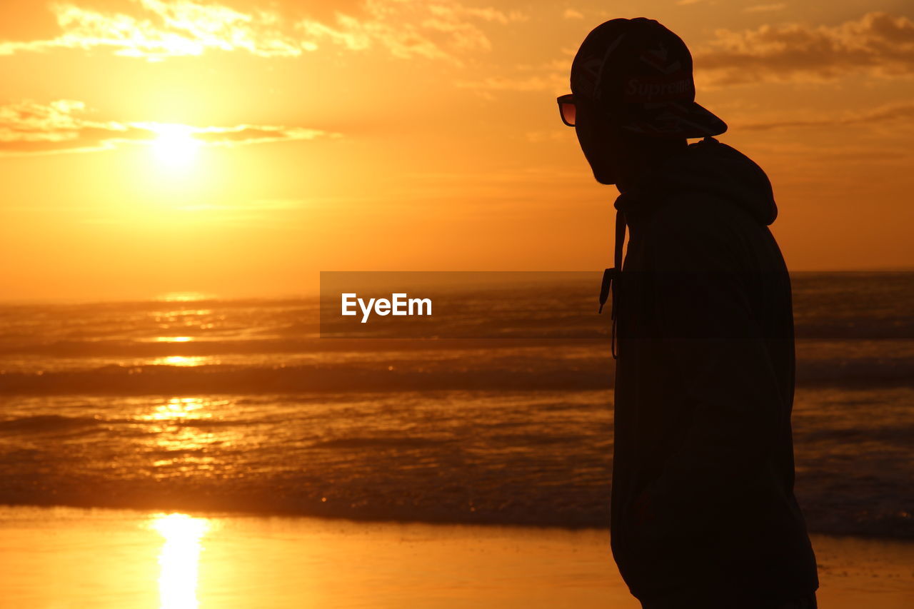 SILHOUETTE MAN LOOKING AT SEA AGAINST ORANGE SKY