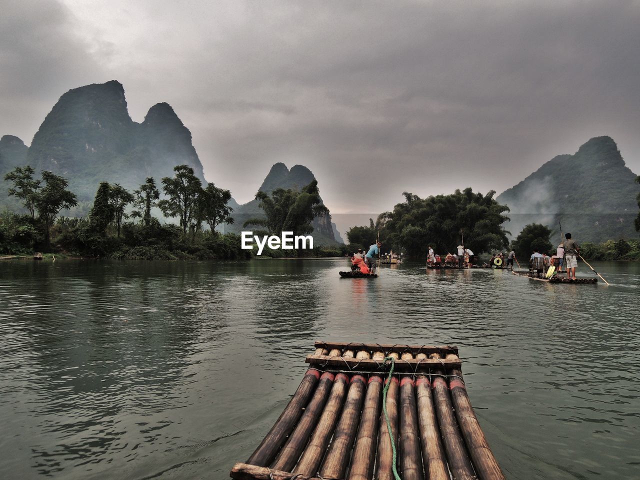 Wooden rafts in river against cloudy sky