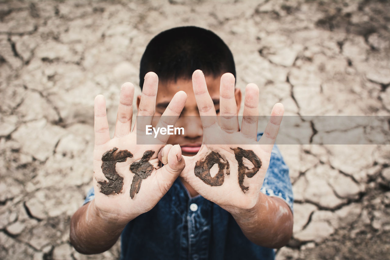 Boy with stop text on hands