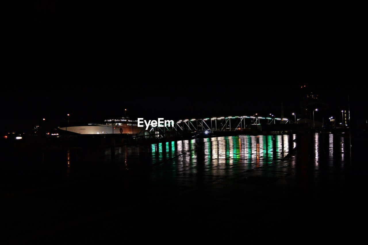 Illuminated bridge over river against sky at night