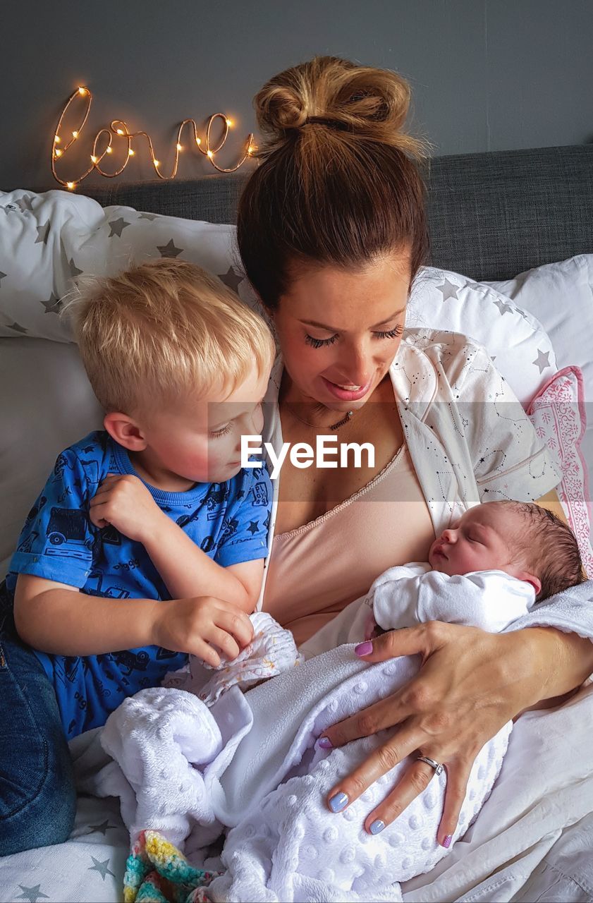 High angle view of mother with children on bed at home