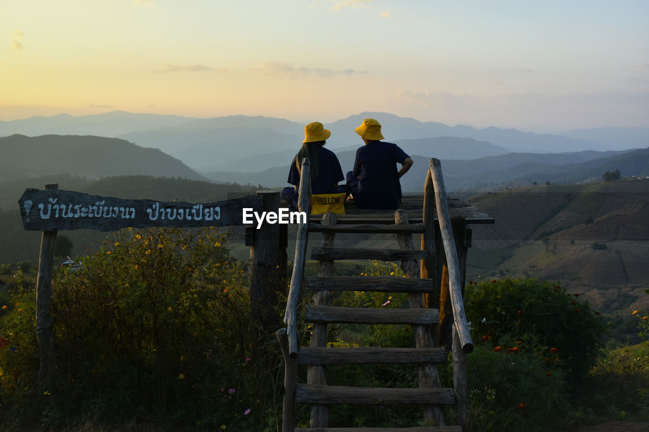 Rear view of men standing on mountain against sky