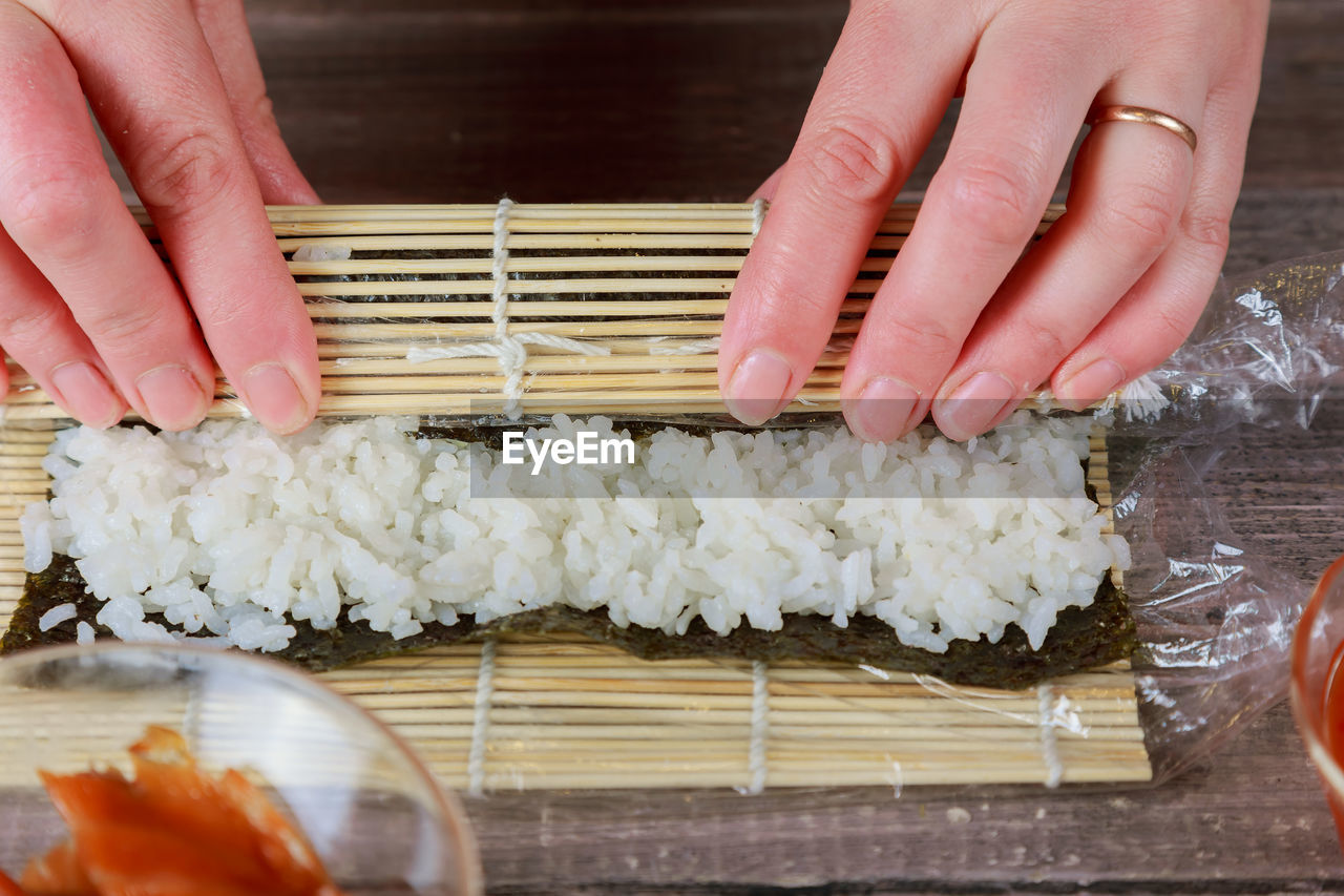 Cropped hands preparing sushi on table