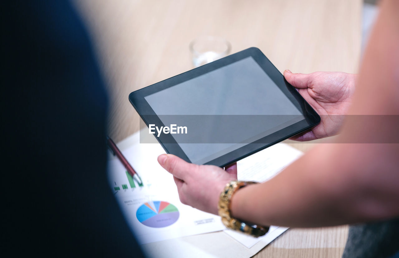 Cropped image of businesswoman using digital tablet with colleague in office